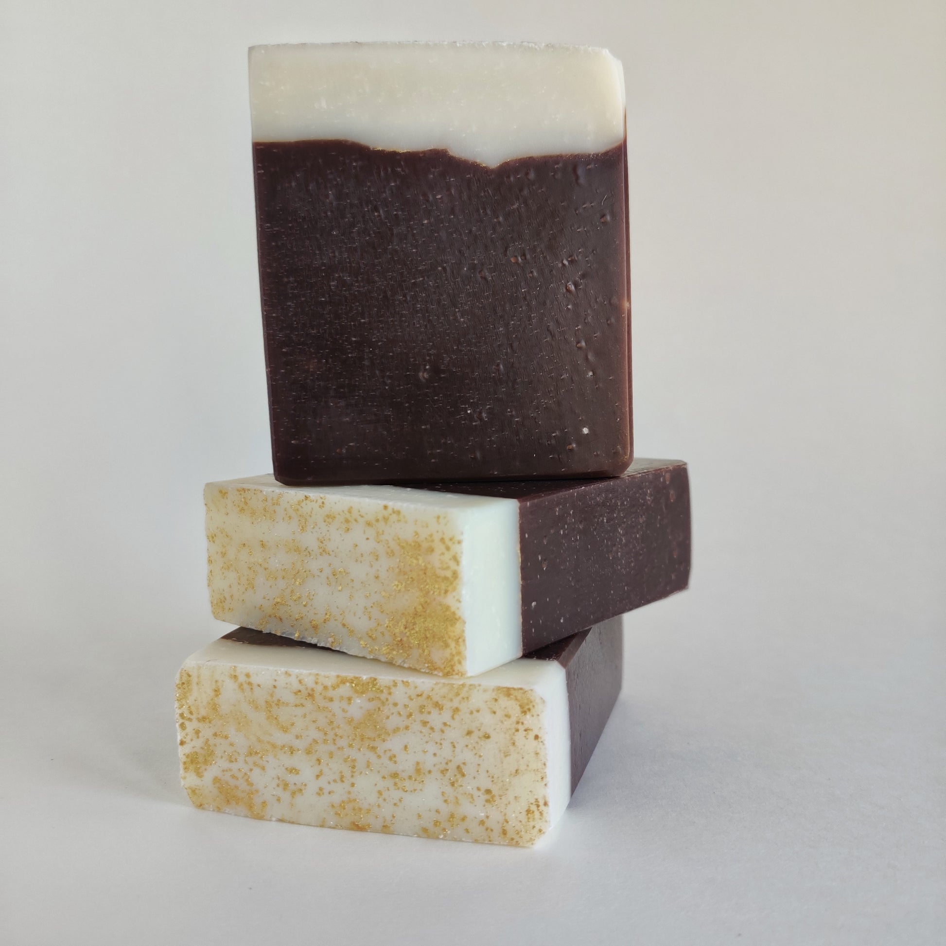 Product photo of three bars of soap from the front and top. The soap is decorated with white and brown layers separated by a gold pencil line. The top is features gold decoration.